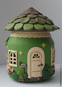 a green ceramic pot with a house on it