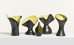 four black and yellow vases sitting next to each other on a white table top