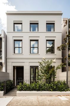 an apartment building with many windows and plants on the sidewalk in front of it's entrance