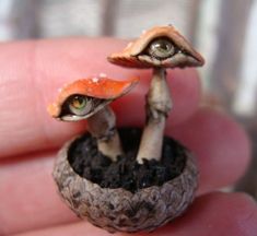 two tiny figurines are sitting in a potted plant with dirt on the ground