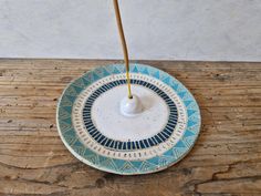 a blue and white plate with a yellow stick sticking out of the top on a wooden table