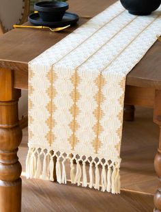 a wooden table topped with a white and yellow table runner next to a black bowl