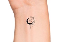 the sun and moon tattoo is shown on the left side of the arm, which has a cross in it