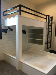 a white bunk bed sitting in a bedroom next to a wall mounted shelf and ladder