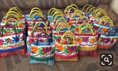 many colorful bags sitting on top of a couch next to each other, all decorated in different colors and designs