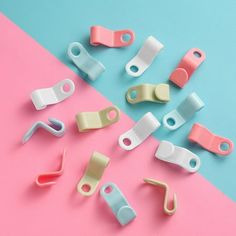 several different colored plastic clips on a pink and blue background