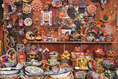 there are many plates and bowls on the shelves in this room, all decorated with colorful designs