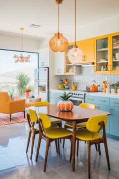 a dining room table with yellow chairs and an orange lamp hanging from the ceiling above it