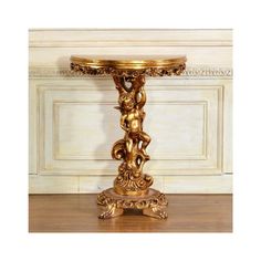 an ornately decorated table with gold paint on the top and bottom, in front of a white wall