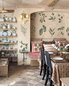 a living room filled with furniture and walls covered in floral wallpaper, next to a dining table