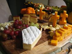 various cheeses and fruits are arranged on a cutting board