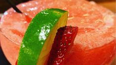 a close up of a drink in a glass with a slice of fruit on the rim