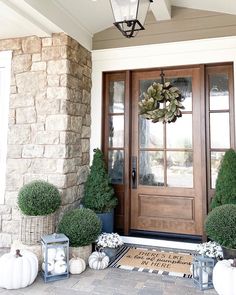 the front door is decorated with white pumpkins and greenery