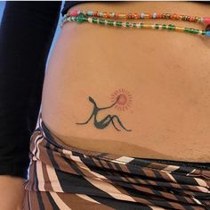 a woman's stomach with a tattoo on the side and colorful beads around her waist