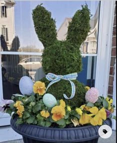 a potted plant with an easter bunny made out of moss and flowers in front of a window