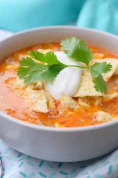 a bowl of soup with sour cream and cilantro garnish on top