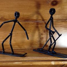 two black metal figurines standing next to each other on a wooden table top