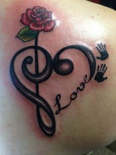 a tattoo on the back of a woman's shoulder with music notes and a rose