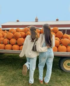 two girls standing in front of a truck full of pumpkins