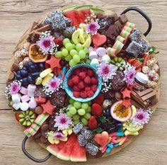 a platter filled with fruit and chocolates on top of a wooden table,