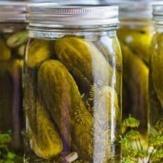 three jars filled with pickles sitting on top of a table