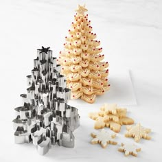 cookie cutters and christmas tree shaped cookies on a white countertop with snowflakes