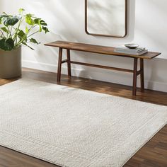 a white rug with a wooden bench and mirror on the wall in front of it