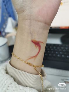 a woman's wrist with a red and yellow bird tattoo on her left arm