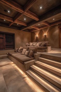 a home theater with couches and pillows on the steps leading up to the screen