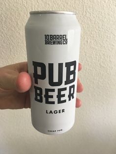 a hand holding a can of beer in front of a white wall with the words pub beer on it