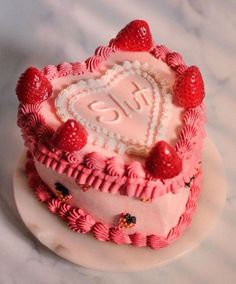 a heart shaped cake decorated with strawberries and icing on a marble table top