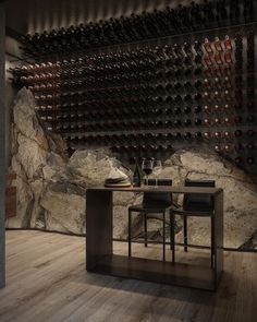 a dining room table with two chairs and wine bottles on the wall