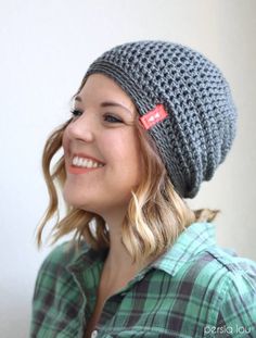 a smiling woman wearing a crocheted hat with a red tag on it's ear