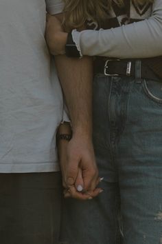 two people standing close together with their hands on each other's shoulders and one holding the hand of another person