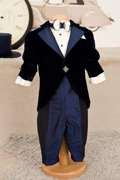 a mannequin dressed in a tuxedo and bow tie stands next to a clock