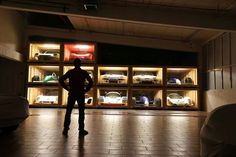 a man standing in front of a display case filled with cars