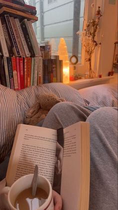 a person is reading a book and holding a cup of coffee in front of them