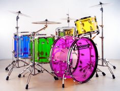 a colorful drum set is sitting on the floor in front of a white background and there are drums behind it