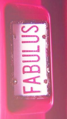 a close up of a license plate on a pink suitcase with the word fabulous spelled in red