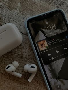 an iphone and earphones on a wooden table