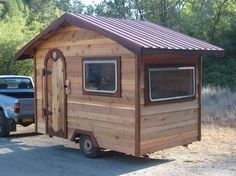 a small wooden cabin sitting on the side of a road next to a pick up truck