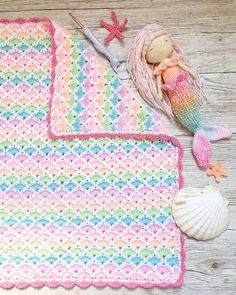 a crocheted blanket with a mermaid doll next to it