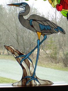 a stained glass bird sitting on top of a window sill