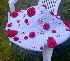 a crocheted hat with strawberries on it sitting on a chair in the grass