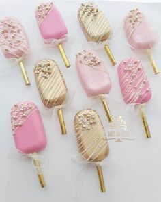 some pink and gold candy pops are on a white table