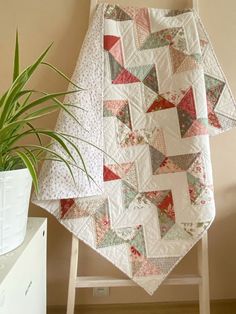 a potted plant sits next to a quilted blanket on a chair in front of a wall