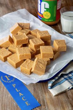 pieces of peanut butter fudge sitting on top of a wooden table next to a bottle of milk