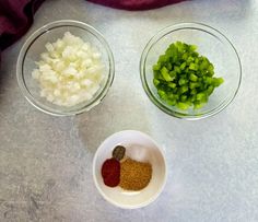 three bowls with chopped onions and seasonings in them