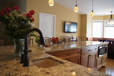 a kitchen with marble counter tops and an island in front of a tv mounted on the wall