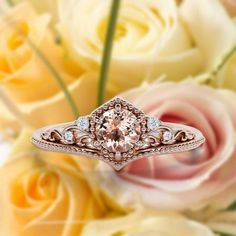 a pink diamond ring sitting on top of some white and yellow flowers with roses in the background